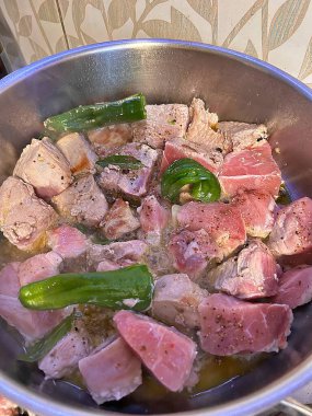 Doğranmış et, tencerede güveç, yeşil asma biber, domuz eti.