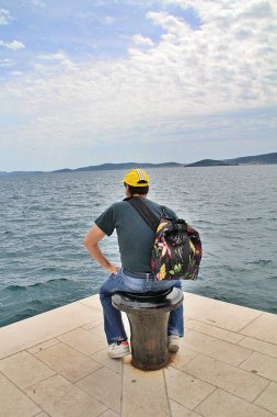 Sahilde oturan bir adam, deniz kenarına bakan bir adam, tefekkür.