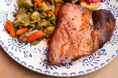 Karışık sebzeli ızgara domuz pirzolası ve dekoratif tabakta kızarmış patates..