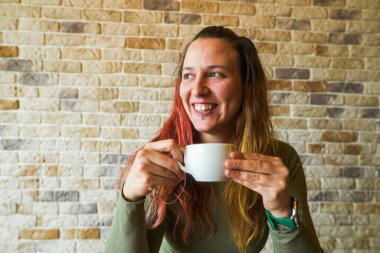 Kahvede elinde kahve fincanı tutan gülümseyen kadın..