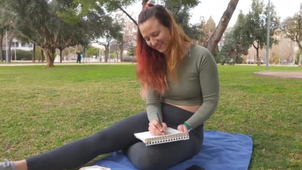 Una Mujer Alegre Sentada Una Manta Azul Parque Dibujando Cuaderno — Vídeos de Stock