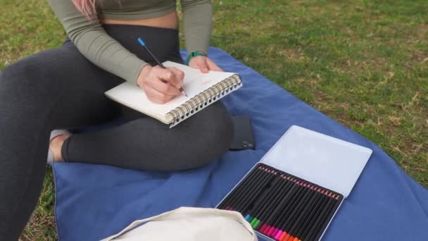 Focused Woman Sketching Notebook While Sitting Cross Legged Blue Blanket — Stock Video