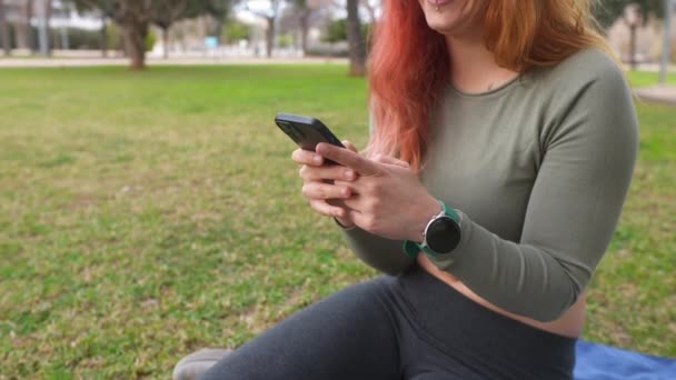 Una Mujer Sentada Hierba Enfocada Smartphone Con Reloj Inteligente Muñeca — Vídeos de Stock