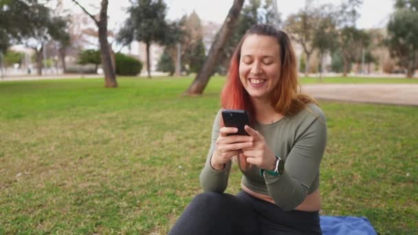 Mujer Sonriente Mirando Teléfono Mientras Está Sentada Aire Libre Una — Vídeos de Stock