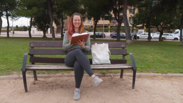 Mujer Sentada Banco Del Parque Leyendo Libro Con Una Bolsa — Vídeos de Stock