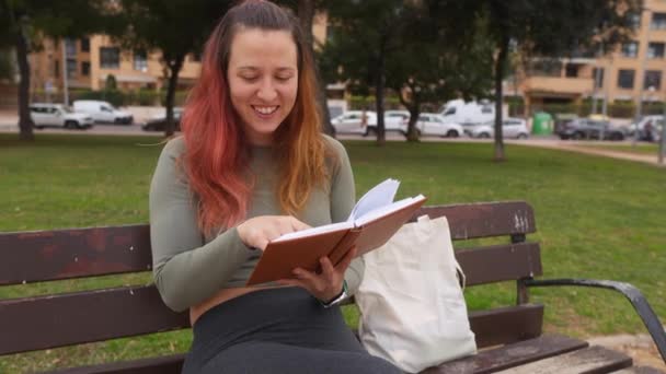 Mujer Feliz Riendo Mientras Lee Libro Banco Parque Público — Vídeos de Stock