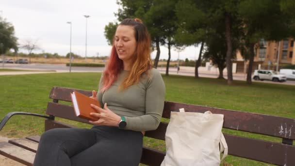 Kvinna Packar Gladeligen Bok Bärkasse Parkbänk — Stockvideo