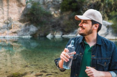 Dağlarda sakin bir nehirde su içen bir adam..