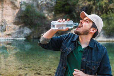 Nehir kenarında su şişesi tutan düşünceli bir adam..