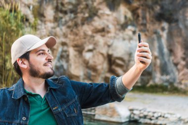 Adam dışarıda akıllı telefonuyla selfie çekiyor..