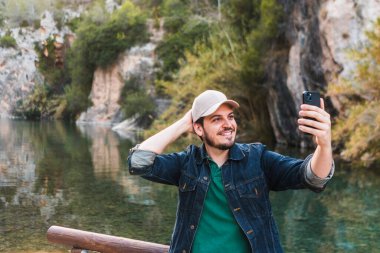 Gülümseyen adam nehir kenarında selfie çekiyor..