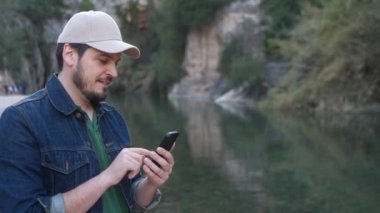 Montanejos 'da nehir kenarında akıllı telefon kullanan bir adam..