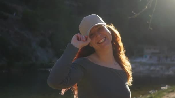 Радісна Жінка Налаштувала Свою Шапку Біля Берега Річки Монтаніосі Сонці — стокове відео