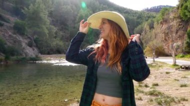Bir kadın hasır şapkasını düzeltirken Montanejos, Castellon 'daki Mijares Nehri' nin doğal güzelliğinin tadını çıkarıyor..