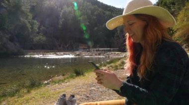Güneşli bir günde Montanejos, Castellon 'da nehir kenarında akıllı telefon kullanan gülümseyen bir kadın..