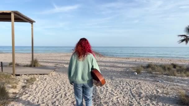 赤毛の女性とクラシックギターが地中海のビーチを歩く — ストック動画