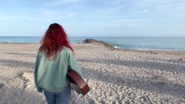 赤毛の女性とクラシックギターは地中海のビーチで海に向かって歩きます — ストック動画