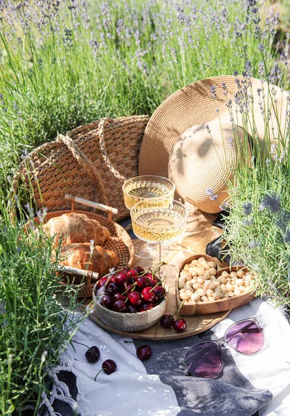 stock image Summer picnic on a lavender field with champagne glasses and cherry berries