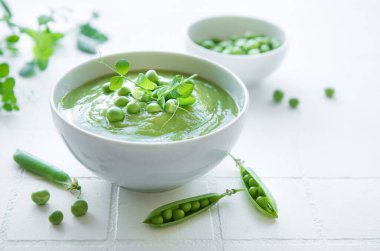 Fresh green pea soup bowl on gray concrete background