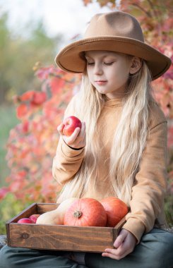 Sonbahar bahçesinde saman balyalarının ve balkabaklarının arasında oturan küçük kızlar
