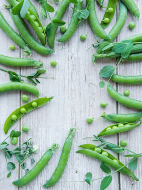 Ahşap arka planda yaprakları olan yeşil bezelyeler.