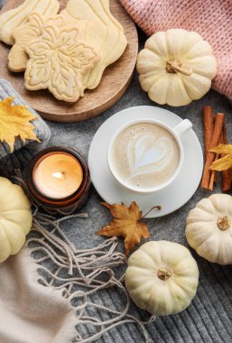Sonbahar kompozisyonu. Sıcak ev atmosferinde mum, kurabiye, kuru yapraklar, dekoratif balkabakları ve terli örgü