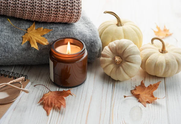 stock image Autumn composition. Cozy home atmosphere with candle, notepad, dry leaves,  decorative pumpkins and knitted sweate