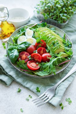 Taze yaz salatası roka, kırmızı kiraz domatesleri fesleğen, yumurta ve avokado. Vejetaryen yemeği. Sağlıklı salata