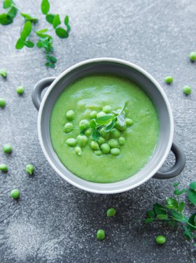 Fresh green pea soup bowl on gray concrete background