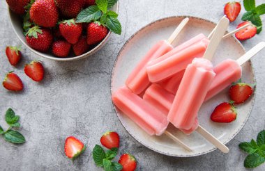 Homemade frozen strawberry ice cream popsicles and fresh strawberries on a concrete background. Summer dessert clipart