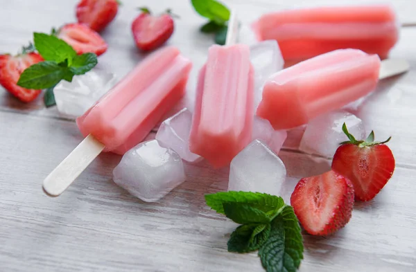 Homemade frozen strawberry ice cream popsicles and fresh strawberries on a concrete background. Summer dessert