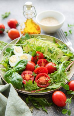 Taze yaz salatası roka, kırmızı kiraz domatesleri fesleğen, yumurta ve avokado. Vejetaryen yemeği. Sağlıklı salata
