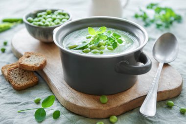 Fresh green pea soup bowl on gray concrete background