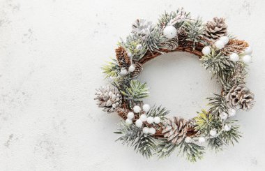Dekoratif Noel çelengi. Çelenk, köknar ağacı ve gri beton zemin üzerindeki koni ağacından yapılmıştır. Noel süslemeleri