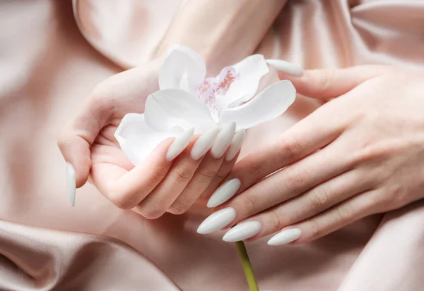 Piękne Dłonie Młodej Kobiety Białym Manicure Paznokciach Beżowy Jedwabne Tło — Zdjęcie stockowe