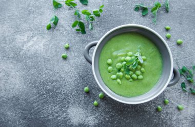 Fresh green pea soup bowl on gray concrete background
