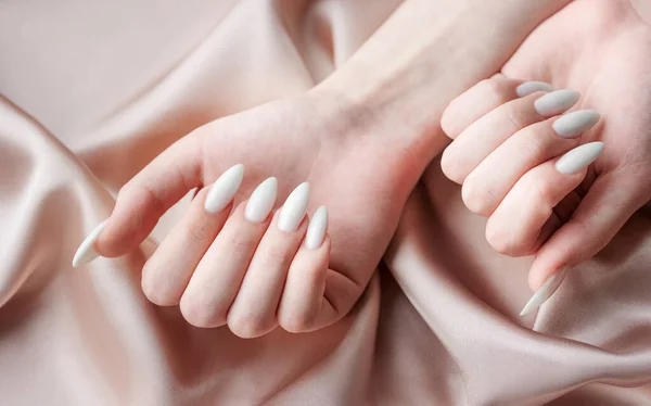 Belas Mãos Uma Jovem Com Manicura Branca Pregos Fundo Seda — Fotografia de Stock