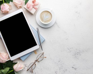 Beton arka planda gül buketi ve tablet. Üst görünüm.