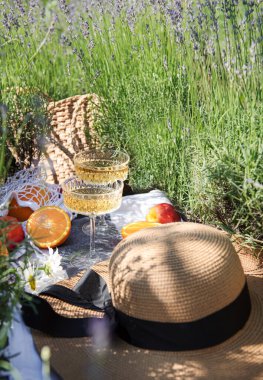 Summer picnic on a lavender field with champagne glasses and fruits