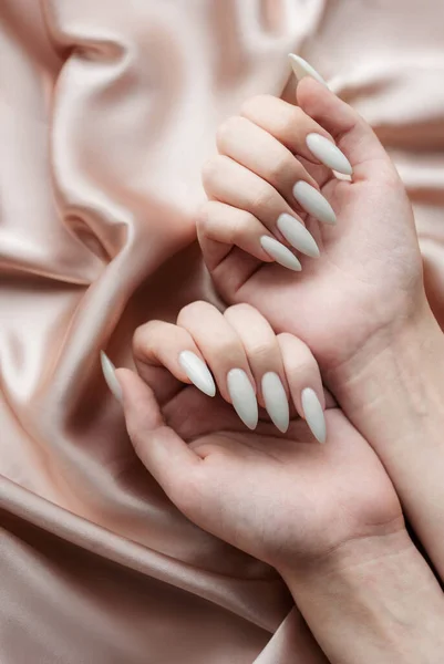 Piękne Dłonie Młodej Kobiety Białym Manicure Paznokciach Beżowy Jedwabny Tło — Zdjęcie stockowe