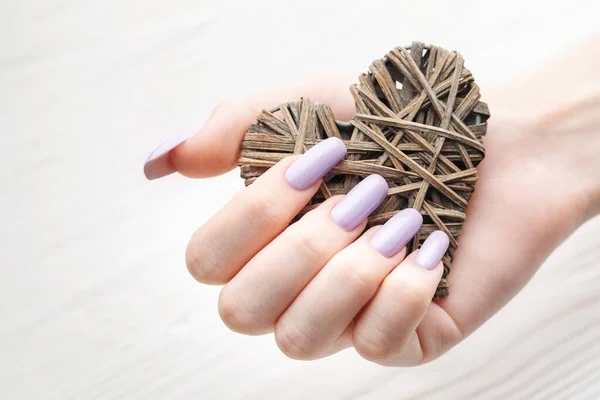 Trendy female manicure. Woman\'s hands with  violet manicure  an decorative heart. Beauty and spa concept.  Valentine day concept.