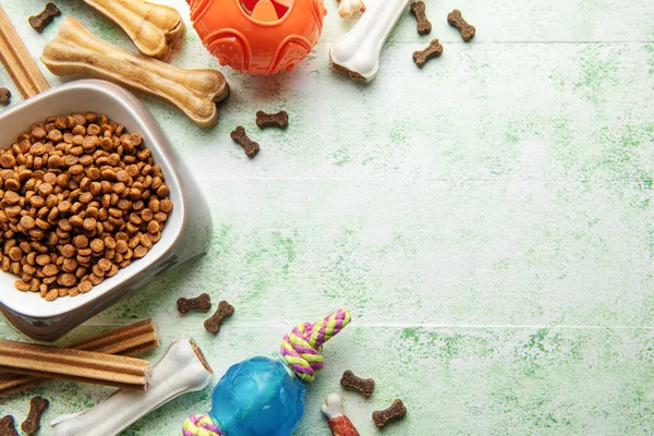 A bowl with dog food, dog treats and toys on a wooden floor. Concept of healthy food for dogs.