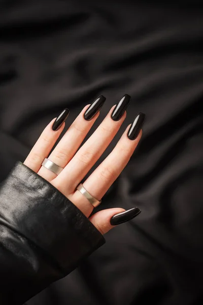 Hands of young girl with black  manicure on nails on black  background