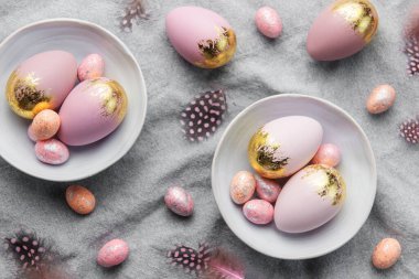 Easter eggs are painted with gold and violet paint on a gray linen background. Concept of Easter holidays. Festive background.