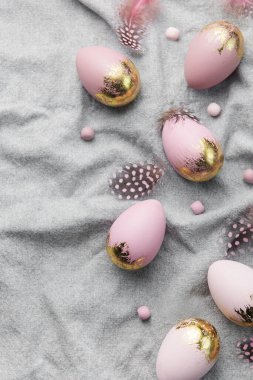 Easter eggs are painted with gold and violet paint on a gray linen background. Concept of Easter holidays. Festive background.