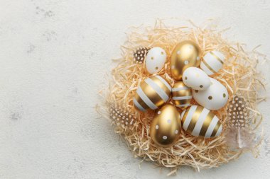 Easter eggs painted with gold paint on a straw background. Concept of Easter holidays. Festive background.