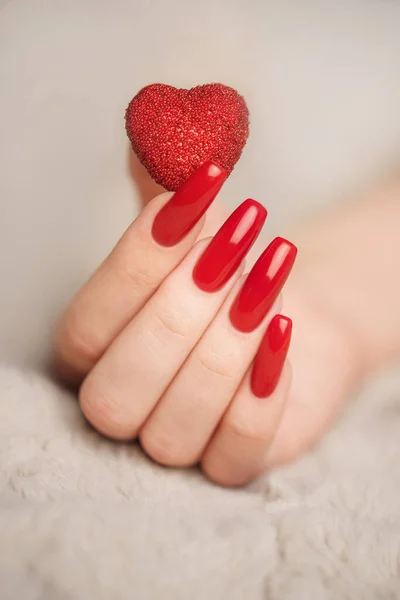 Trendy female manicure. Woman\'s hands with  red an decorative heart. Beauty and spa concept.  Valentine day concept.