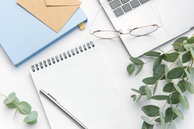 Modern white office desk table with laptop, notebook and other supplies. Blank copy space for  the text. Top view, flat lay.
