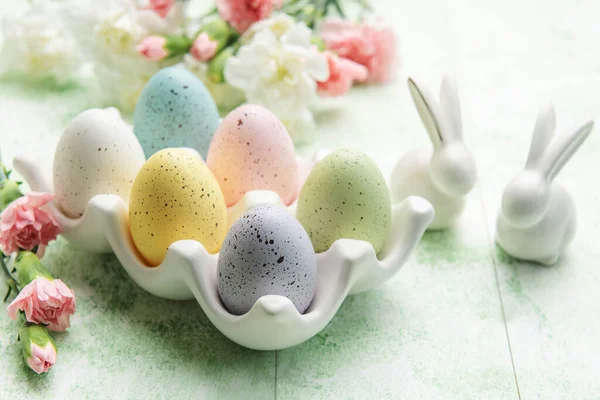 Easter decor. Colored Easter eggs on a ceramic stand and decorative rabbits. The concept of preparation for the celebration.