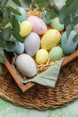 Easter decor. Colored Easter eggs in a wooden box on the table. The concept of preparing for the celebration.